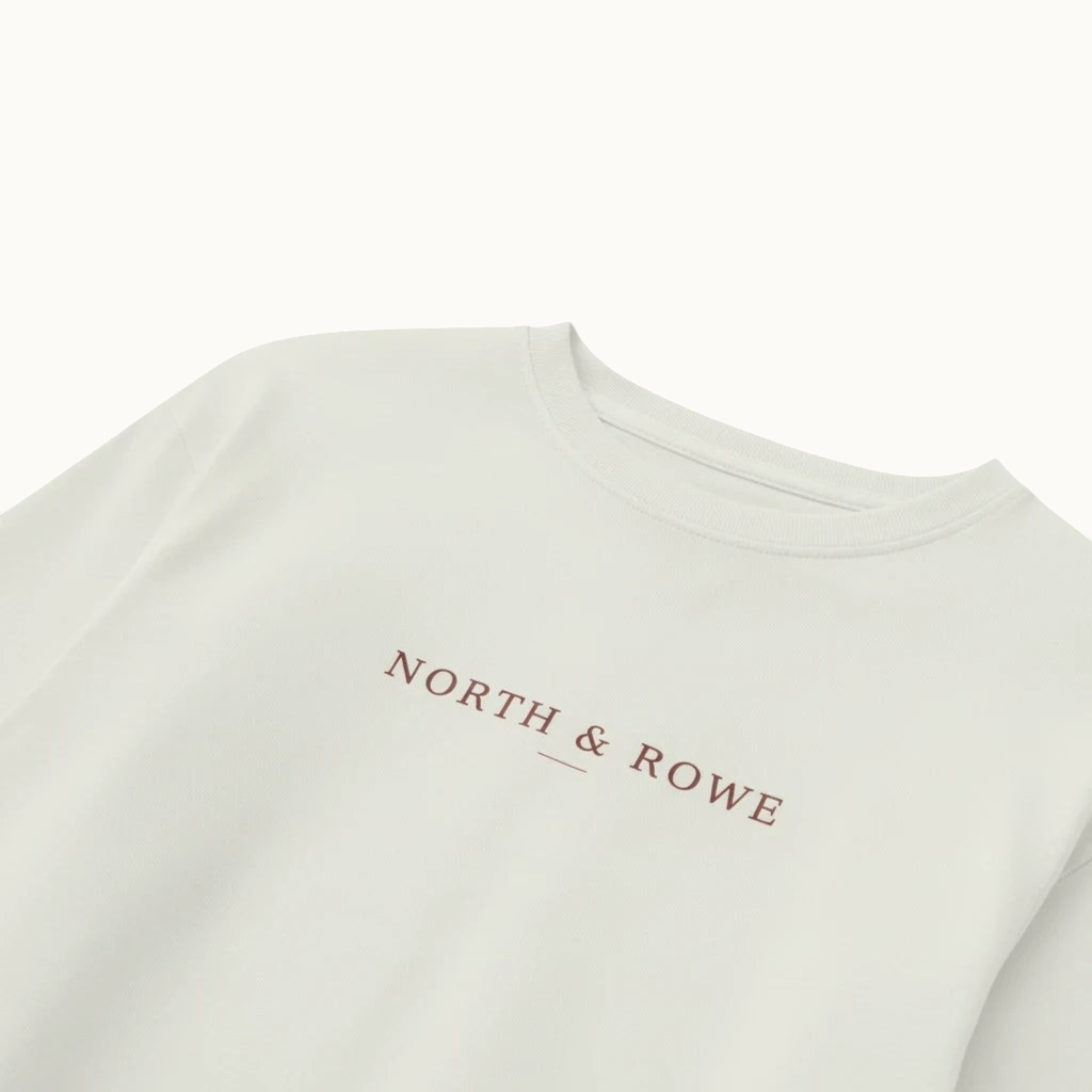 North & Rowe long sleeve crewneck shirt in off-white with a minimalist brown logo printed on the chest.
